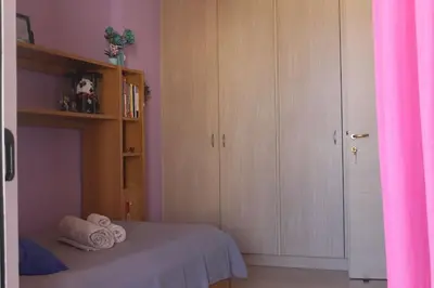 a bedroom with a bed with wooden cabinets and towels at Maria's Airport Apartment, 4' metro, 10' airport, 15' beach, 40' city center in Koropíon