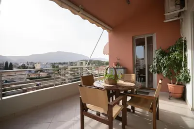 a balcony with a table and chairs and a view at Maria's Airport Apartment, 4' metro, 10' airport, 15' beach, 40' city center in Koropíon