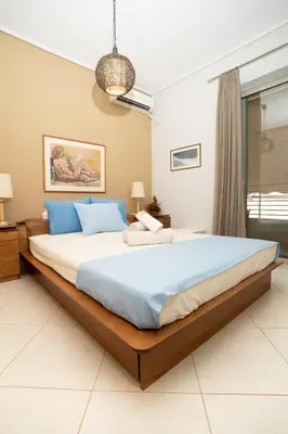 a bedroom with a large bed with blue pillows at Maria's Airport Apartment, 4' metro, 10' airport, 15' beach, 40' city center in Koropíon