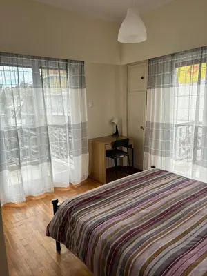 a bedroom with a bed and a desk and windows at Комната с общей баней karolou 10 in Athens