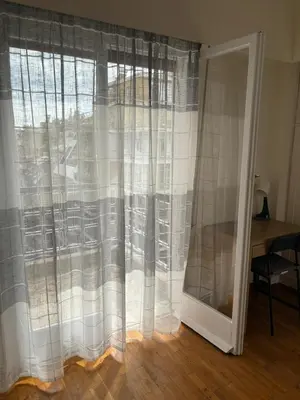 a window with white curtains in a room with a desk at Комната с общей баней karolou 10 in Athens