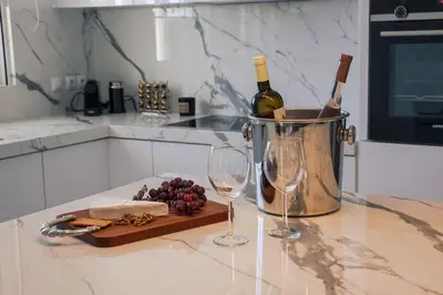 a counter with two wine glasses and a bucket of grapes at Lagonisi Luxury Escape in Lagonissi