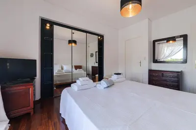 a bedroom with a large white bed and a television at Lagonisi Luxury Escape in Lagonissi