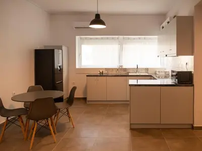 a kitchen with a table and a black refrigerator at Prasa in Piraeus