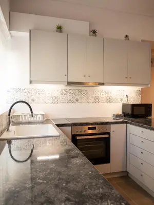a kitchen with white cabinets and a sink at Prasa in Piraeus