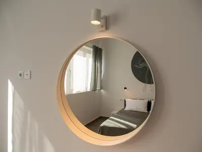 a round mirror in a room with a bed at Prasa in Piraeus