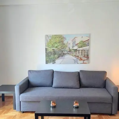 a living room with a couch and a painting on the wall at Sunny apartment in Acropolis in Athens