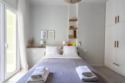 a white bedroom with a bed with towels on it at ARIS Central Athens in Athens