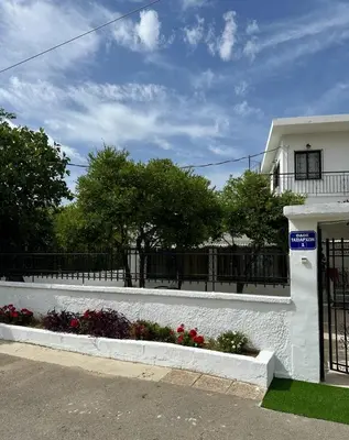 a white building with a fence and flowers at Only Sun in Papangeláki