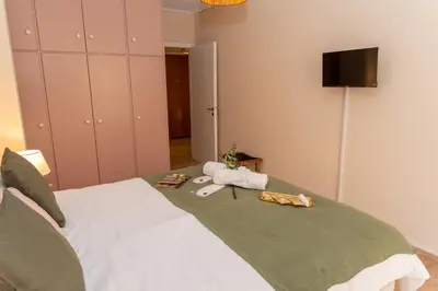 a bedroom with a bed with towels and a television at Athena Cocooning Apartment in Piraeus