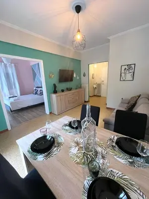 a dining room with a table and a living room at MediTerra Stay Athens Riviera in Athens
