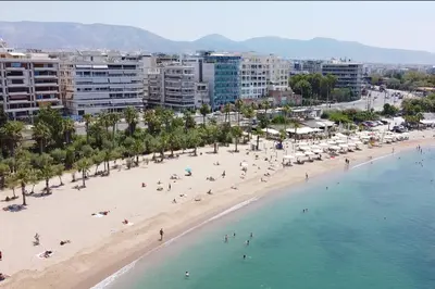 a beach with people in the water and buildings at MediTerra Stay Athens Riviera in Athens