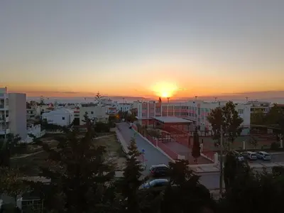 a sunset over a city with cars parked in a parking lot at Cozy Room with Sea View in Athens