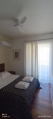 a bedroom with a bed and a window with white curtains at Cozy Room with Sea View in Athens