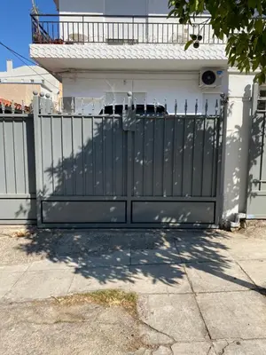 a black gate in front of a house at Apostolis Apartment, Argyroupoli, Athens in Athens