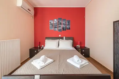 a bedroom with a large bed with red walls at Rigas apartment in Ilioupoli Athens in Athens