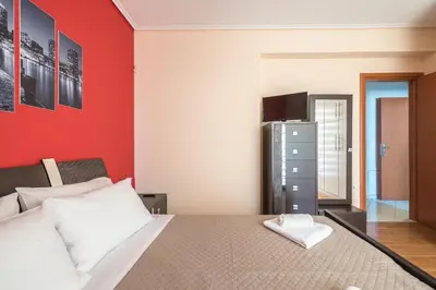 a bedroom with a bed and a red wall at Rigas apartment in Ilioupoli Athens in Athens