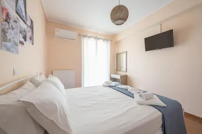 a bedroom with a white bed with a tv on the wall at Rigas apartment in Ilioupoli Athens in Athens
