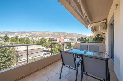 a balcony with a table and chairs and a view at Rigas apartment in Ilioupoli Athens in Athens