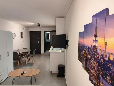 a living room with a table and a tv on a wall at Studio Stratos ideal for 2-3 night Weekends in Athens