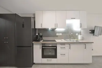 a kitchen with white cabinets and a stainless steel refrigerator at Studio Stratos ideal for 2-3 night Weekends in Athens