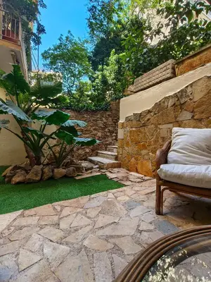 a patio with a stone wall and a couch and grass at Zen Garden, 600m from Acropolis Museum in Athens