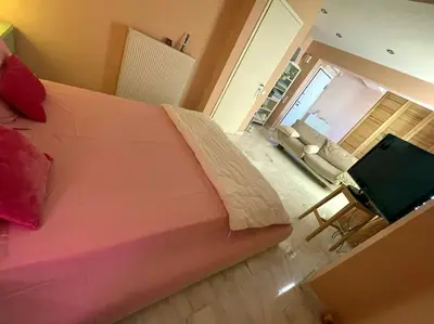 a bedroom with a large pink bed and a couch at Lovely Maisonette & Parking in Athens