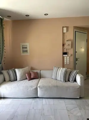 a living room with a white couch with pillows at Lovely Maisonette & Parking in Athens