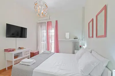 a white bedroom with a bed and a tv at Faliron Urban Retreat in Athens