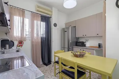a kitchen with a yellow table and a yellow table and chairs at Faliron Urban Retreat in Athens