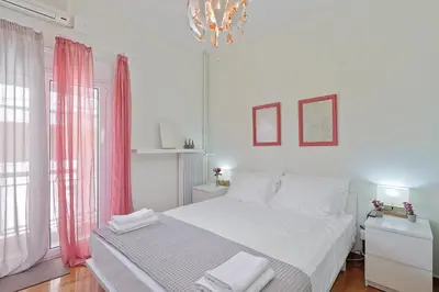 a white bedroom with a bed and a chandelier at Faliron Urban Retreat in Athens