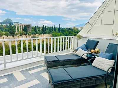 a balcony with two chairs and a couch on a balcony at Acropolis Compass Residence in Athens