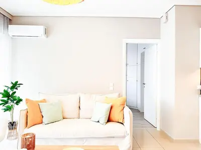 a white couch in a living room with orange pillows at Pame Rentals - Chic Alimos Home, 5 Min Walk to the Beach in Athens