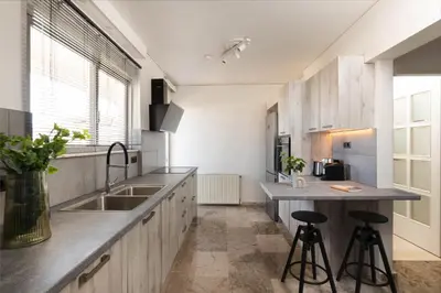 a kitchen with a sink and a counter with stools at Modern Escape 2BR Apartment in Glyfada by UPSTREET in Athens