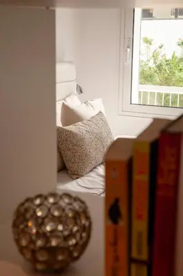 a book shelf with a bowl of balls next to a window at Raise Varkiza Serenity Suite in Vari