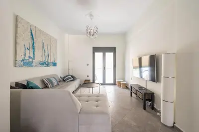 a white living room with a couch and a tv at Sempre il Mare in Piraeus