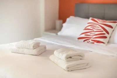 three towels are stacked on a white bed at Sempre il Mare in Piraeus
