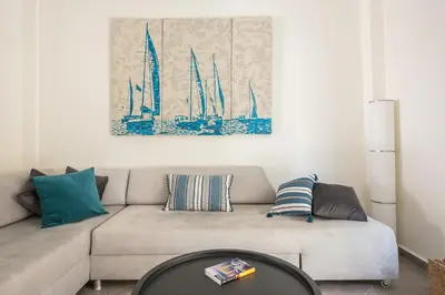 a living room with a couch and a painting of sailboats at Sempre il Mare in Piraeus