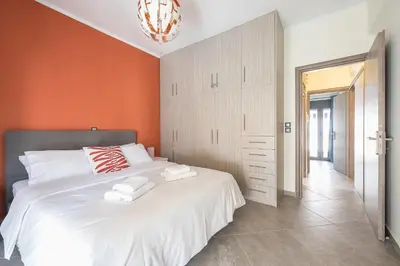 a bedroom with a large white bed with an orange wall at Sempre il Mare in Piraeus