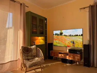 a living room with a flat screen tv and a chair at Filoxenia Harmony Retreat in Keratea