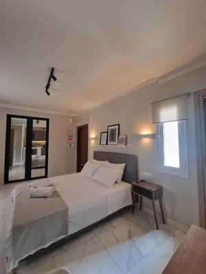 a white bedroom with a large bed and a window at Órrhaon Athens in Athens