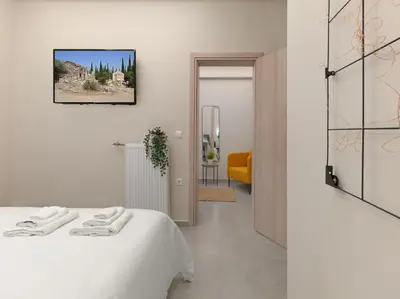 a white bedroom with a bed and a yellow chair at Formionos95 in Athens