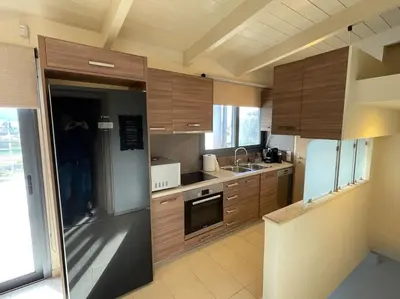 a kitchen with wooden cabinets and a stainless steel refrigerator at Porto - luxury penthouse, pool, walk to the beach in Porto Rafti