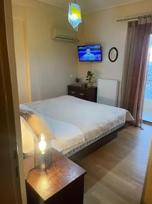 a bedroom with a bed and a table and a tv at newly built apartment with amazing view in Athens