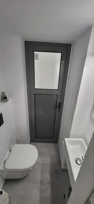 a bathroom with a door with a toilet and a sink at Stella's Cozy Apt (By Marina Zeas) in Piraeus