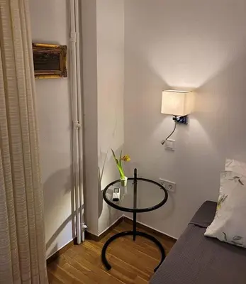 a room with a table with a lamp and a bed at Charming veranda in Exarcheia in Athens