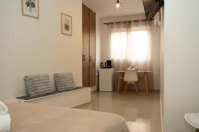 a bedroom with a bed and a table and a window at Anesis Airport Rooms 408 in Koropíon
