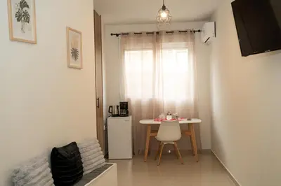 a small room with a table and a refrigerator at Anesis Airport Rooms 408 in Koropíon