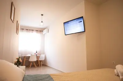 a bedroom with a flat screen tv on the wall at Anesis Airport Rooms 408 in Koropíon