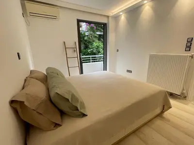a large bed in a room with a window at Kavouri Retreat, Only pines hide the sea in Athens